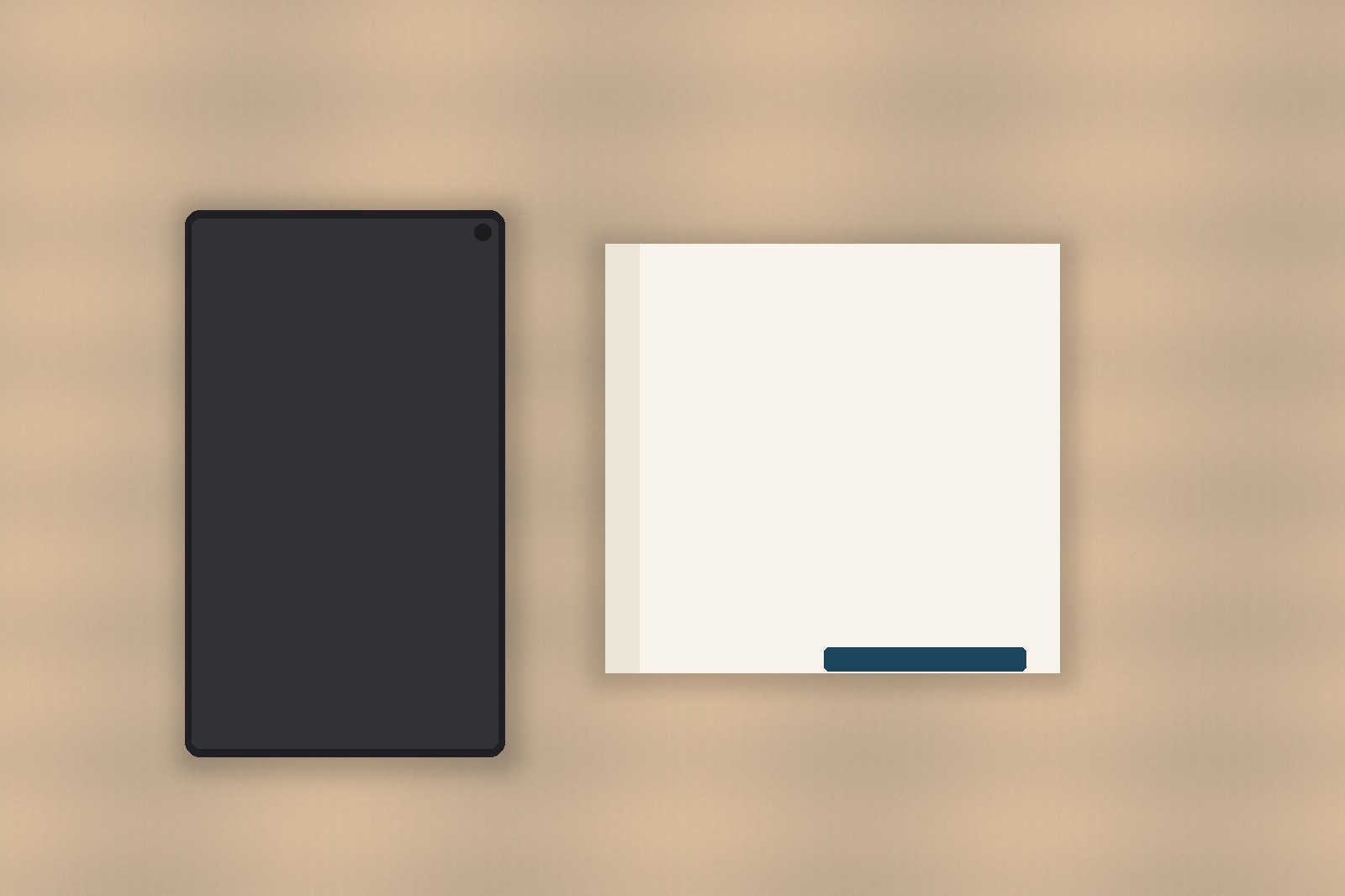 A phone face down, a blank notebook, and a pen on a pale wooden desk